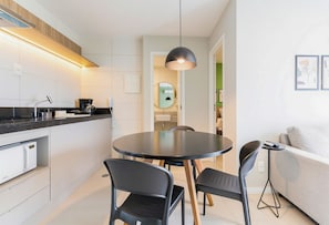 A modern kitchen with a dining area, a round table, and a sofa. - Parque do Cais #1109 With Sea View by Carpediem (Recife)