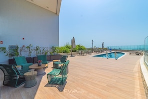 A rooftop pool area with green wicker furniture and a clear view of the city skyline. - Parque do Cais #1109 With Sea View by Carpediem (Recife)