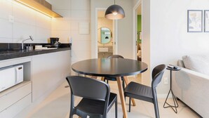 A modern kitchen with a dining area, a round table, and a sofa. - Parque do Cais #1109 With Sea View by Carpediem (Recife)