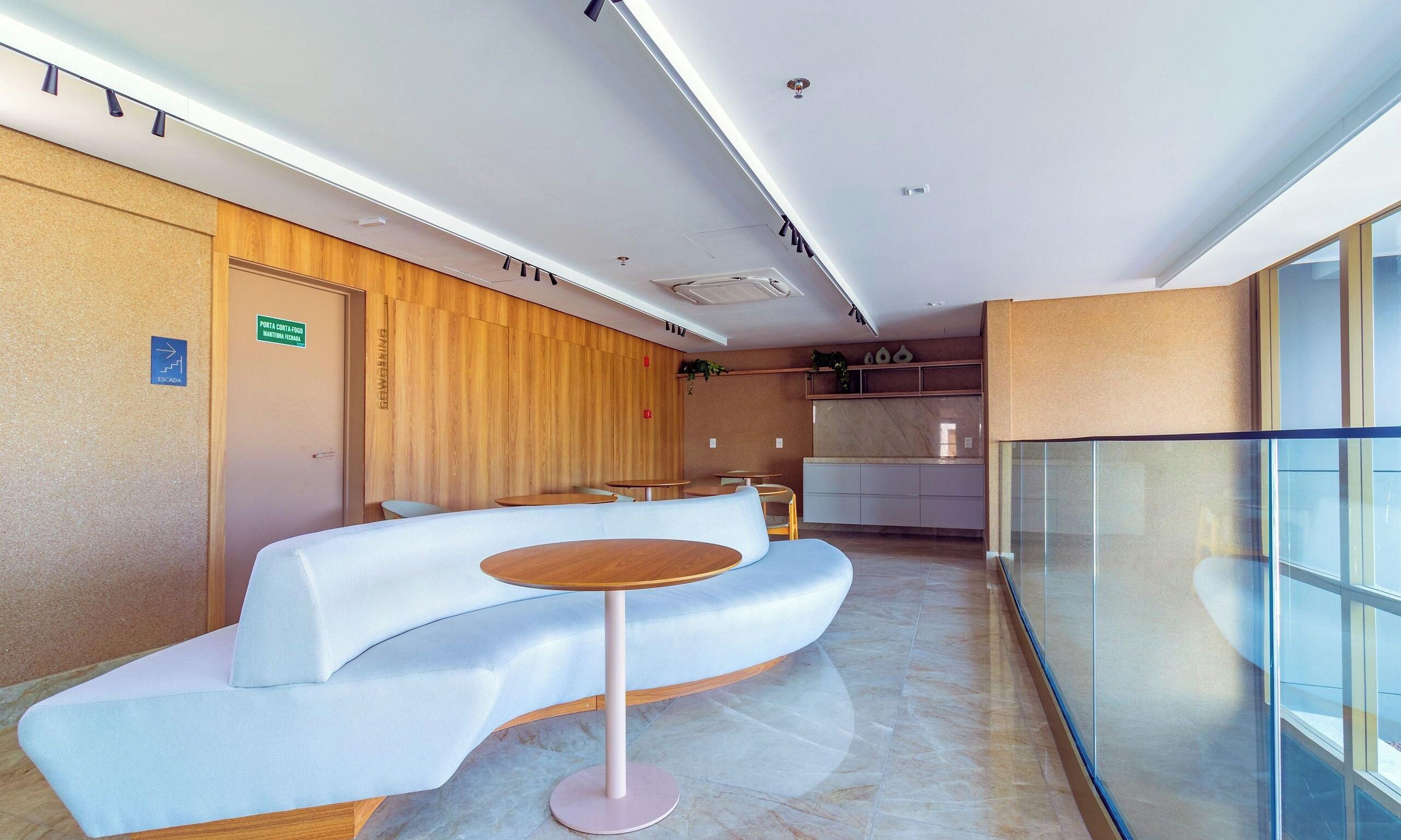 Un'area d'attesa moderna con una reception a forma di arco, un tavolo rotondo e un pannello di vetro.