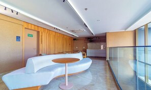 A modern waiting area with a curved reception desk, a round table, and a glass partition. - Parque do Cais #1109 With Sea View by Carpediem (Recife)