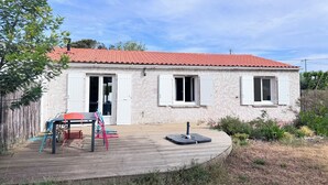A house with a red-tiled roof, a wooden deck, and a fenced yard. - Pointeau House (Saint-Georges-d'Oléron)