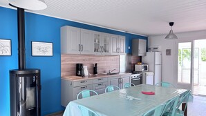 A modern kitchen with white cabinets, a stove, and a dining area with a table and chairs. - Pointeau House (Saint-Georges-d'Oléron)