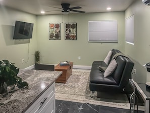 Una sala de estar con televisor, sofá, mesa de centro y ventilador de techo.