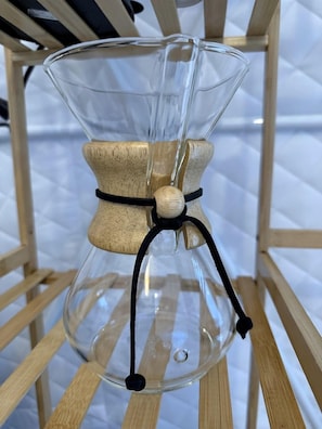 A clear glass hourglass with a cork stopper and a black string tied around it, hanging on a wooden shelf. - Dome Tent Retreat with Private Wood-Fired Hot Tub in Branchville, South Carolina (Branchville)