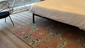 Quarto tipo tenda com cama, uma cadeira e uma janela grande.