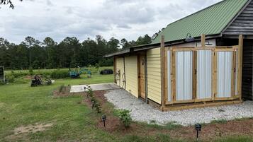 A single-story building with a green roof, a gravel driveway, and a small garden area with plants.