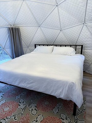 Un lit dans une chambre aménagée comme une tente, avec un sol à motifs.