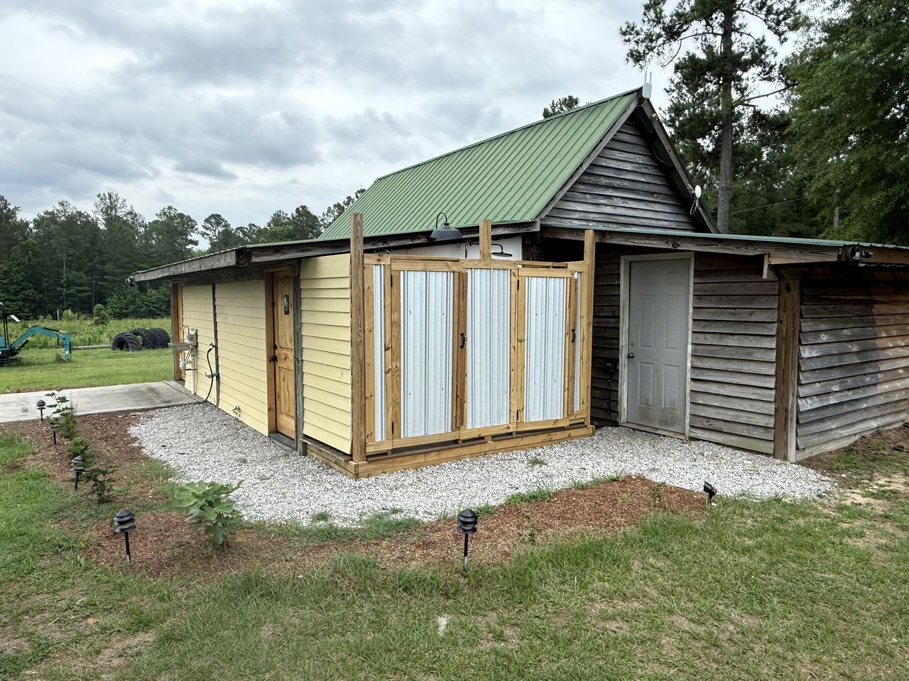 A single-story building with a green roof, a wooden door, and a small attached garage.