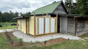 A single-story building with a green roof, a wooden door, and a small attached garage.