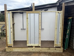 Estructura de madera con tres paneles verticales, posiblemente un mueble o unidad de almacenamiento, con una puerta de metal y una escalera apoyada.