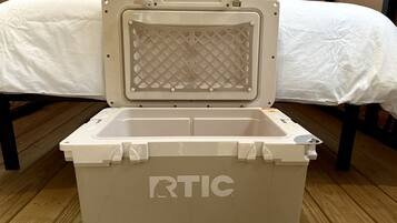 Refrigerador portàtil blanc amb la marca 'RTIC' al costat, posat sobre un terra de fusta.