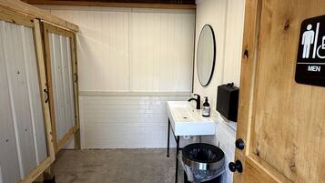 A men's restroom with a sink, mirror, and trash can.