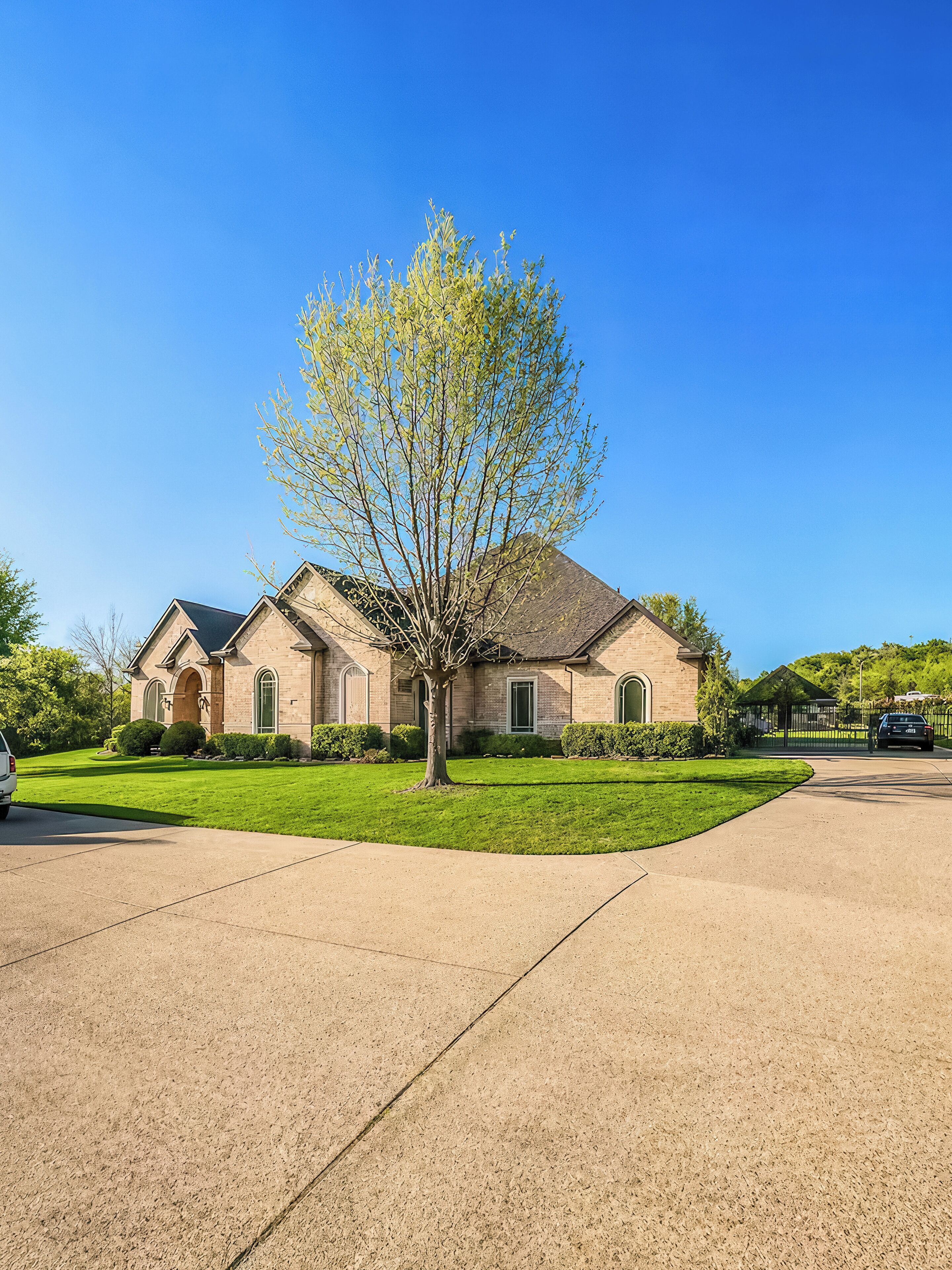 A two-story house with a driveway, a lawn, and a tree in front.