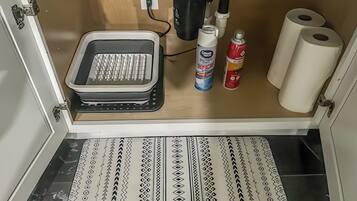 A kitchen with a built-in toaster, a coffee maker, a bottle of dish soap, and two rolls of toilet paper.