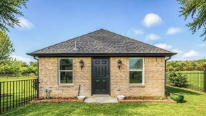 A small brick house with a black door, two windows, and a front yard. - Guest Villa (Cedar Hill)