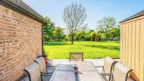 An outdoor patio with a table and chairs, a brick wall, and a wooden shed. - Guest Villa (Cedar Hill)
