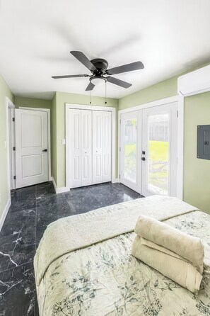 Un dormitorio con cama, ventilador de techo y vista a un césped verde.