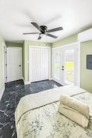 Un dormitorio con cama, ventilador de techo y vista a un césped verde.