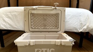 A white portable cooler with the brand 'RTIC' on the side, placed on a wooden floor. - Canvas Cabin with Camp Grill and Cozy Outdoor Retreat in Branchville, South Carolina (Branchville)