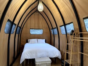Une tente avec un lit, un lustre et une échelle.