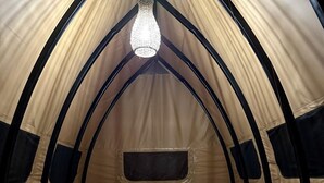 A tent-style room with a bed, a small table, and a hanging light fixture.