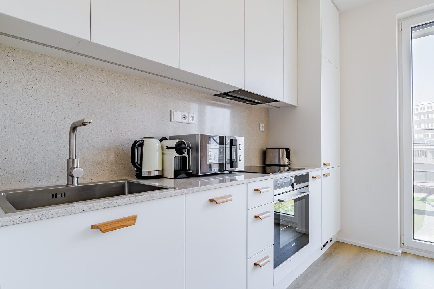 Een moderne keuken met een roestvrijstalen spoelbak, een waterkoker, een broodrooster en een magnetron.