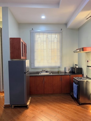 Uma cozinha compacta com geladeira, fogão, micro-ondas e armários de madeira.