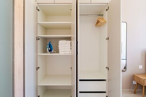 Ein Kleiderschrank mit geöffneten Türen, der Regale und Ablageflächen zeigt.