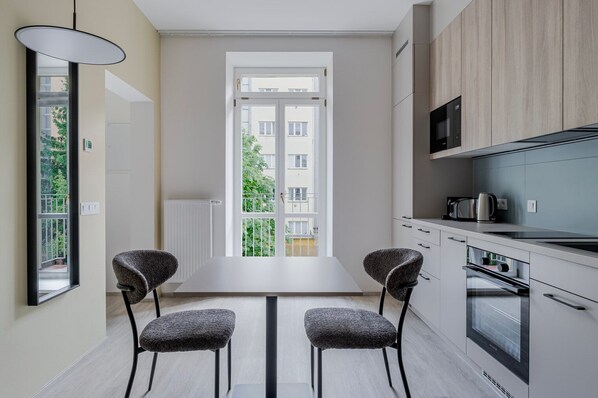 Eine moderne Küche mit Essbereich, großen Fenstern und Blick auf ein Wohngebäude.