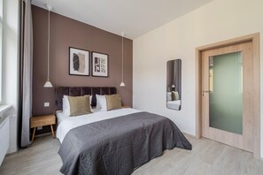 Ein Schlafzimmer mit Bett, Nachttischen, einem Spiegel und Kunstwerken an der Wand.