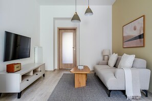 Ein modernes Wohnzimmer mit Flachbildfernseher, Couch, Holz-Couchtisch und einer Lampe.