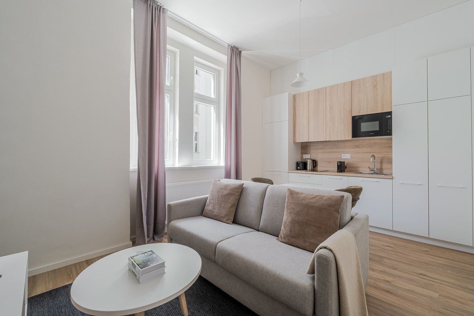 Eine moderne Wohnung mit einer Couch, einem kleinen runden Tisch und einer Küchenzeile.