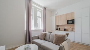 En modern lägenhet med en soffa, ett litet runt bord och ett litet kök.