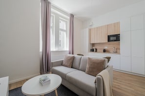 A modern apartment with a sofa, a small round table, and a kitchenette. - Blueground | Holešovice, city view, nr Vltava (PRG-53) (Prague)