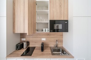 A modern kitchen with wooden cabinets, a built-in microwave, a sink, a kettle, a toaster, and a coffee maker. - Blueground | Holešovice, city view, nr Vltava (PRG-53) (Prague)