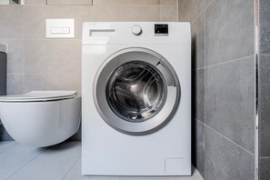 A front-loading washing machine in a bathroom with a toilet. - Blueground | Michle, private garden, nr Vysehrad (PRG-99) (Prague)