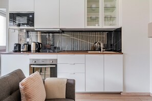 A compact kitchen with a microwave, coffee maker, kettle, and a gas stove. - Blueground | Michle, private garden, nr Vysehrad (PRG-99) (Prague)