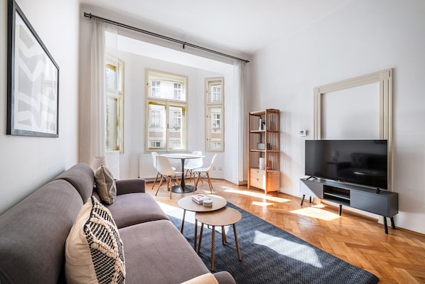 Ein modernes Wohnzimmer mit einer Couch, einem Couchtisch, einer TV-Konsole und einem Bücherregal.