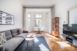 Ein modernes Wohnzimmer mit einer Couch, einem Couchtisch, einem Fernseher und einem Essbereich mit Stühlen und einem Tisch.
