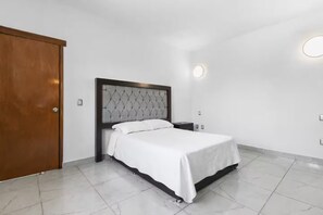 Een slaapkamer met een bed, een houten garderobe en een nachtkastje.