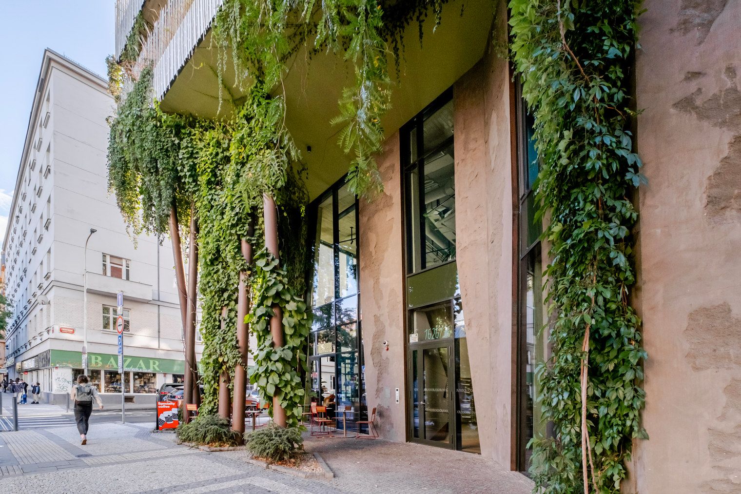 A building with a green storefront and a pedestrian walkway.