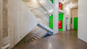 Interior moderno com escada, portas verdes e vermelhas, e piso de concreto.