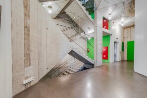 Ein modernes Interieur mit einer Betontreppe, grünen Wänden und einer roten Brandschutztür.