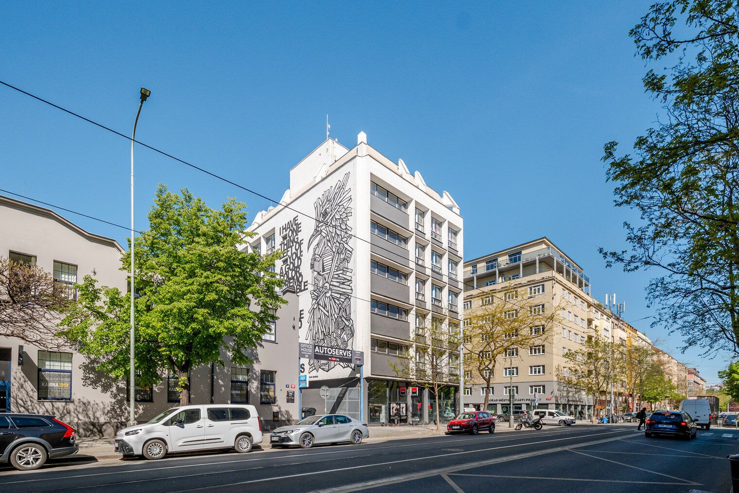A multi-story building with a modern architectural design, featuring a prominent vertical line art installation on its facade.
