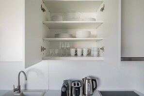 Eine Küche mit weißen Schränken, einer Edelstahl-Spüle, einem Toaster und einem Wasserkocher.