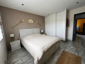 Un dormitorio con cama, mesitas de noche, lámpara, un objeto decorativo en la pared y armario.