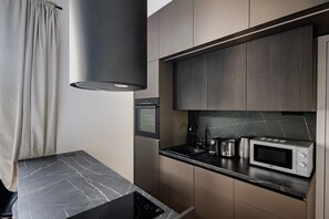 A modern kitchen with a built-in oven, microwave, and toaster, a black marble countertop, and dark cabinetry. - Blueground | Smíchov, rooftop, nr Vltava River (PRG-106) (Prague)