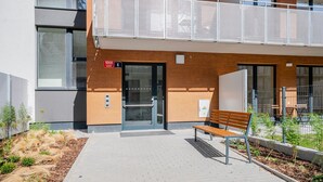 Un edificio de diseño moderno, con un balcón que tiene barandilla metálica, un banco y una puerta marcada con el número 1068.