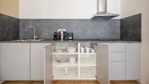 Una cocina con un lavaplatos empotrado, una campana extractora de acero inoxidable y una encimera con cafetera y hervidor.